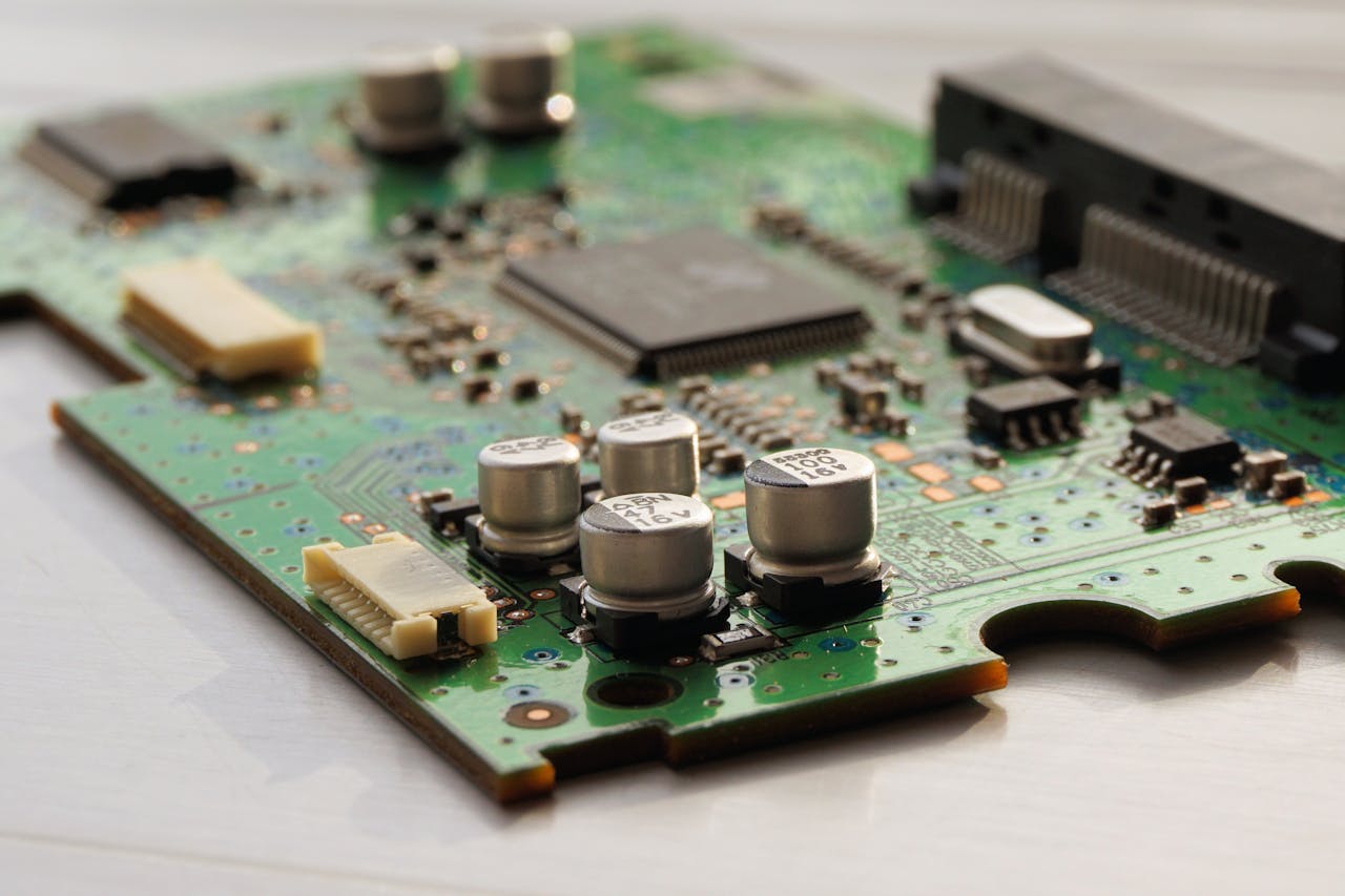 hero-img-01 Detailed view of a green circuit board featuring capacitors and microchips.