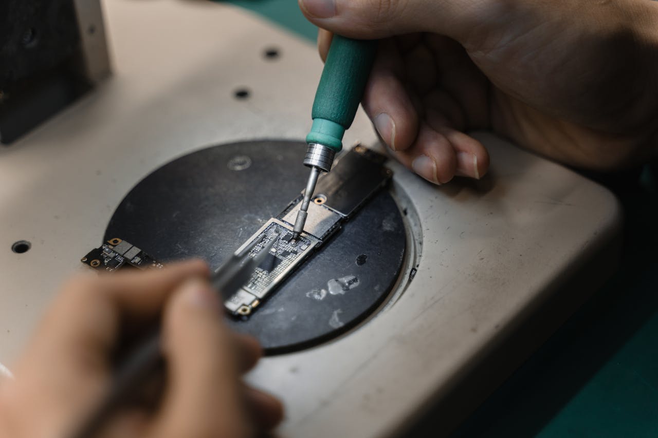 services-03 Hands using a soldering iron on circuit board, showcasing precise electronic repair indoors.
